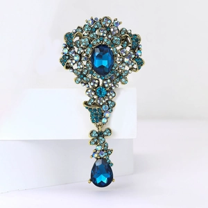 Macro di una spilla vintage in oro con strass blu intenso e ciondolo a goccia d'acqua
