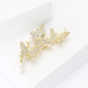 Eleganter Schmetterling-Brosche mit Zirkonia und Perlen auf weißen geometrischen Blöcken
