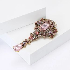 Dettaglio di spilla barocca con cristalli rosa e finiture dorate di alta qualità