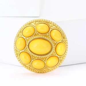 Macro shot of gold-plated alloy brooch featuring elegant yellow gemstones and beads