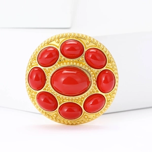 Baroque style gold brooch with large central red stone and intricate beaded edging