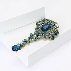 Dettaglio di spilla vintage in lega dorata con strass blu reale ovali e a goccia