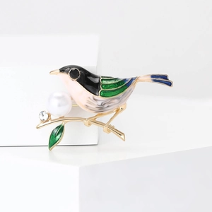 Détail de la broche moineau avec oiseau en émail coloré sur branche dorée et perle