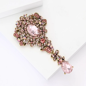Primo piano dettagliato della spilla vintage in lega di bronzo con strass rosa e pendente