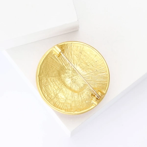 Macro view of the golden alloy brooch back showing textured metal and pin closure