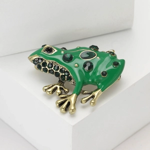 Élégante broche grenouille en émail vert avec cristaux sur support blanc