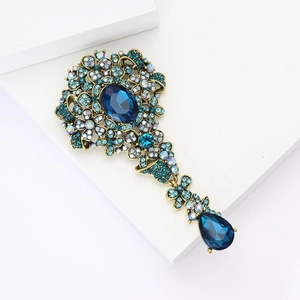 Dettaglio di spilla vintage in bronzo con cristalli blu scuro e pendente a goccia