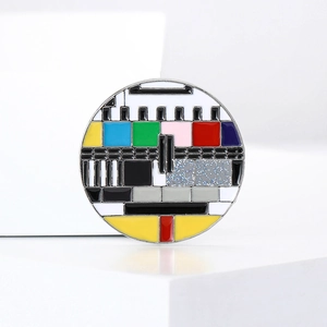 Gros plan d'un pin's rond en émail avec un motif de mire TV rétro colorée classique
