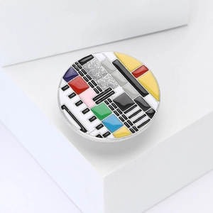 Détail d'un pin's émaillé rétro motif mire TV avec un design de mosaïque colorée