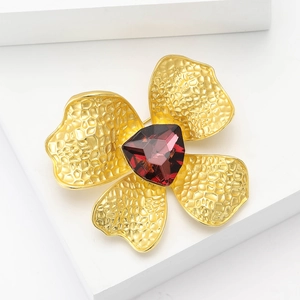 Elegant matte gold flower brooch with red gemstone center and hammered metal petals