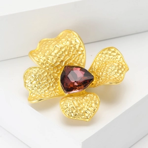 Elegant gold flower brooch with hammered texture petals and a purple crystal center