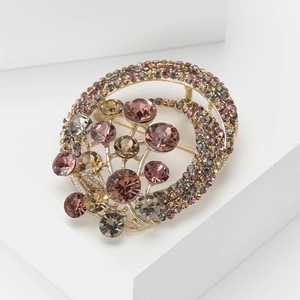 Vintage gold-toned round brooch with colorful rhinestones on a white geometric stand