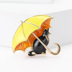 Macro shot of a cute black cat sitting under a yellow enamel umbrella brooch pin