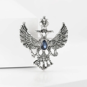 Vista detallada del broche de águila bicéfala plateada con cristal azul y fondo blanco