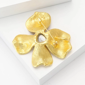 Detail view of the back of a matte gold flower brooch showing the pin clasp mechanism