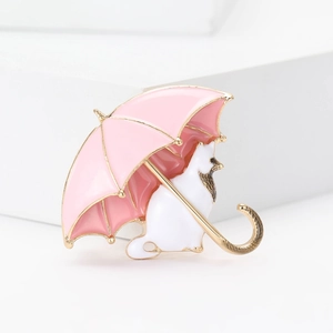 Close-up of white cat with umbrella enamel brooch with elegant gold metallic detailing
