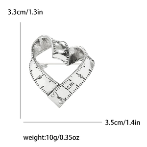 Detailed macro view of heart-shaped measuring tape brooch in vintage silver finish