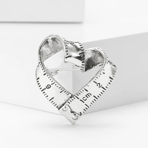 Macro shot of retro heart-shaped tape measure brooch with engraved scale details