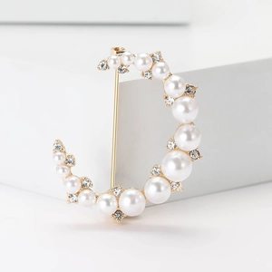Broche élégante en croissant de lune dorée avec perles et strass sur fond blanc