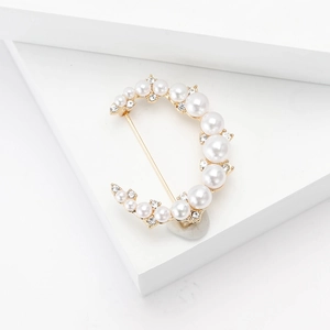 Élégante broche lune avec perles et cristaux sur un présentoir minimaliste