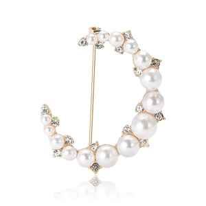 Élégante broche lune dorée avec perles blanches et cristaux sur fond blanc avec reflet