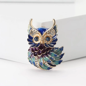 Broche hibou chic en émail avec cristaux et finition dorée sur un décor blanc épuré