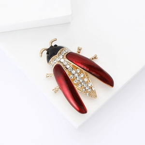 Detailed close-up of a red enamel ladybug brooch with sparkling rhinestones on gold metal