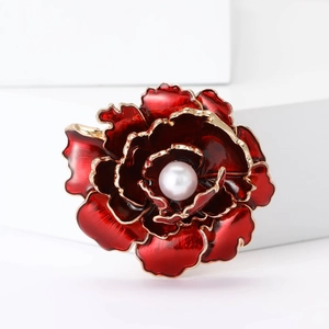 Détail macro de la broche pivoine émaillée rouge avec perle centrale et cadre doré
