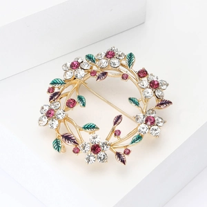Elegant floral wreath brooch with colorful rhinestones and enamel leaves on a gold base