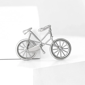 Macro shot of silver bicycle brooch with rhinestones on white minimalist display stand