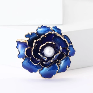 Vue détaillée d'une broche pivoine en émail bleu avec perle blanche et bords dorés