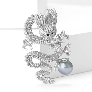 Detailed macro view of silver dragon brooch with white rhinestones and a grey pearl
