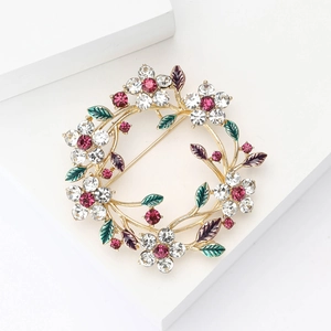 Elegant gold floral wreath brooch with colorful rhinestones and enamel petals on white steps
