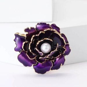 Broche pivoine en émail violet avec bordures dorées et perle sur un support blanc