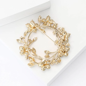 Detail of the golden flower wreath brooch showing the secure metal pin back closure
