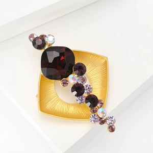 Broche carrée dorée vintage avec strass violets et grande pierre brune sur socle blanc