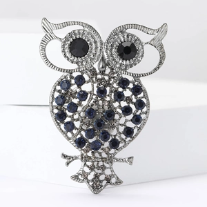 Vintage owl brooch with blue rhinestones and hollow silver alloy body on white background