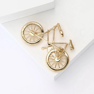Macro detail of a high-end golden bicycle brooch featuring intricate wheel and frame design