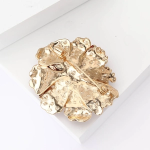 Détail de l'envers de la broche fleur dorée avec texture métallique et épingle de sûreté