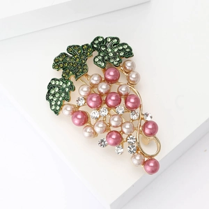 Elegant gold grape brooch with pink pearls and green rhinestone leaves on white background
