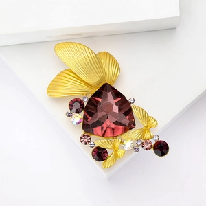 Elegant gold butterfly brooch featuring a large faceted purple gemstone and crystals