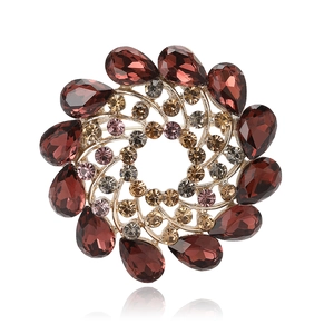 Elegant gold spiral flower brooch with red crystals and rhinestones on white background