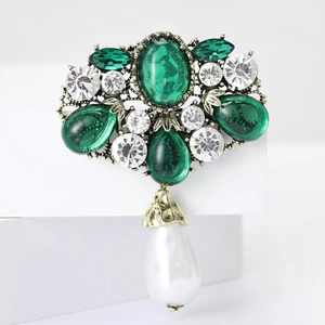 Vintage Baroque brooch with emerald crystals and white pearl drop on a golden base