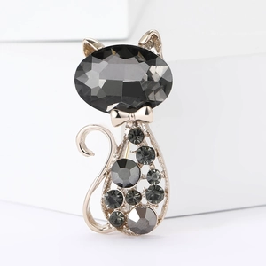 Detail of a cat brooch featuring a large black gemstone head and grey crystal pave body