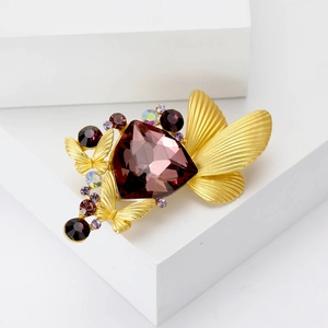Elegant gold butterfly brooch with a large purple faceted crystal and rhinestone accents