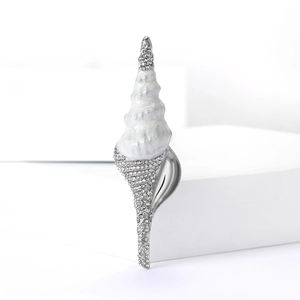 Vue détaillée d'une broche coquillage en métal argenté, strass et émail effet marbre