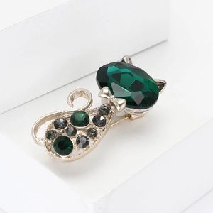 Elegant cat brooch with green crystals and rhinestone details on white background