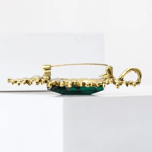 Detailansicht der Vintage-Brosche in Gold mit grünem Stein und rückseitigem Nadelverschluss