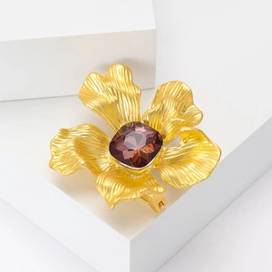 Eleganter Gold-Blumen-Brosche mit mattem Finish und rubinrotem Kristall auf weißem Grund