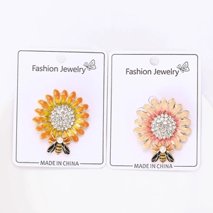 Dettaglio di spille ad ape e girasole con smalto vivace e strass scintillanti